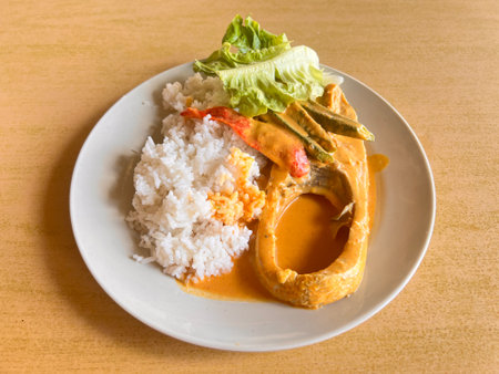 Fresh fish with curry sauce and rice on wooden table, Malaysia foodの写真素材