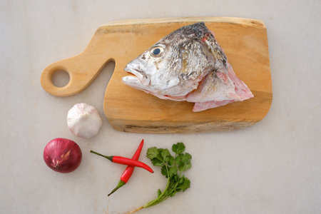 Raw golden snapper heads ready for cooking with some spices on wooden cutting boardの写真素材