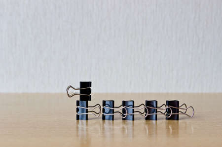 Binder clips figure on wooden table.の写真素材