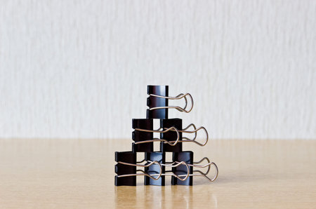 Binder clips pyramid on wooden table.