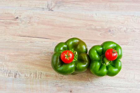 Fresh green peppers and small tomatoes at wooden background. Objects at the right part of imageの写真素材