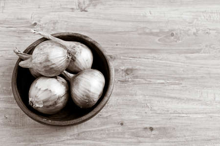 Fresh golden onion bulbs in wooden bowl. Horizontal black and white image. Object at the left part of imageの写真素材