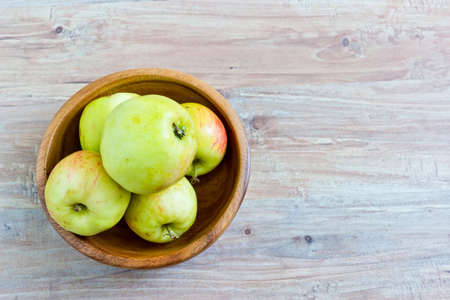 Fresh apples in wooden bowl. Horizontal image. Object at the left part of imageの写真素材