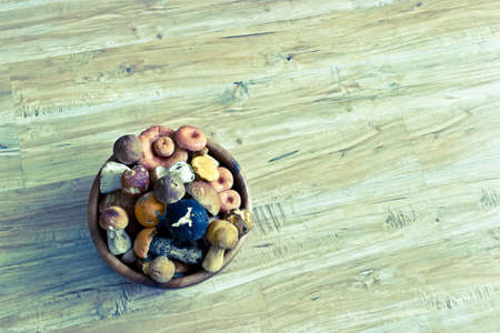 Mixed forest mushrooms in wooden bowl. Image with vintage filterの写真素材