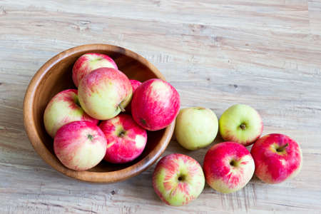 Fresh ripe apples in wooden bowl on wooden backgroundの写真素材