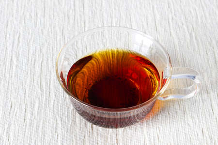 Fresh strong black tea in glass cup on textured linen backgroundの写真素材