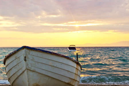 Old wooden fishing boat on the beach at sunriseの写真素材