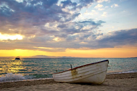 Beautiful sunrise over Aegean sea with lonely fishing boat on beachの写真素材