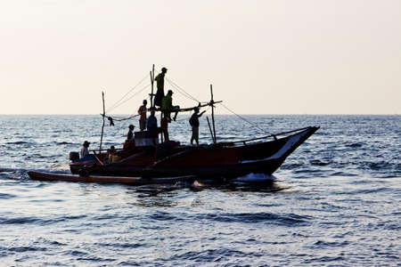 Fishermen on traditional boat in Indian ocean near coast of Sri Lankaの写真素材