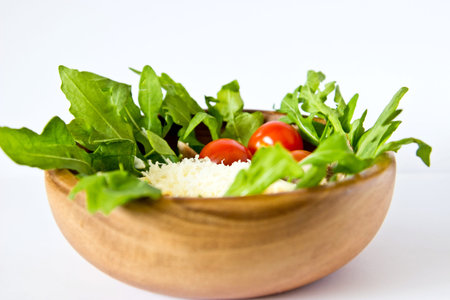 Salad of beef tongue, lettuce, tomatoes, cheese, scrambled eggs with cream and garlic sauce in wooden bowl. Selective focus. On white linen backgroundの写真素材