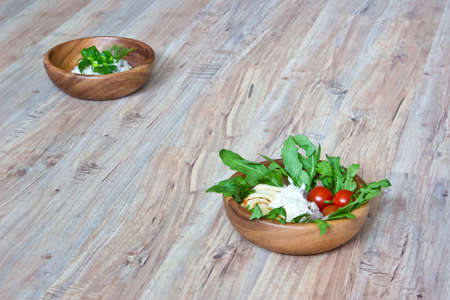 Two kinds of salads in wooden bowls: with vegetables and with beef tongue. Selective focus on wooden backgroundの写真素材