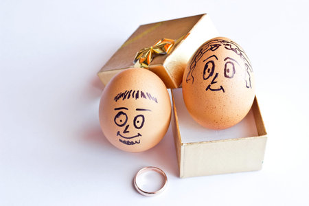 Golden gift box and Painted easter eggs with man and woman smiling faces. Conceptual image with happy couple and wedding rings. Isolated on white backgroundの写真素材