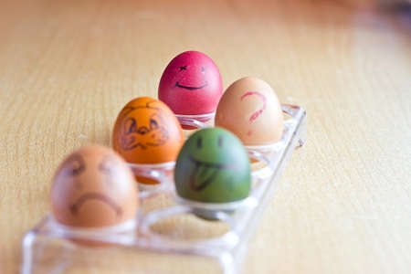 Colored easter eggs with smile faces and question on stand with blurred multicolored backgroundの写真素材