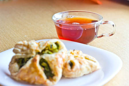 Fresh baked homemade puff pastry cakes with fresh strong black tea in glass cup. Selective focusの写真素材