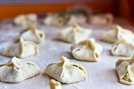 Cooking homemade puff pastry cakes with onion and egg. Focus on foreground, blurred backgroundの写真素材