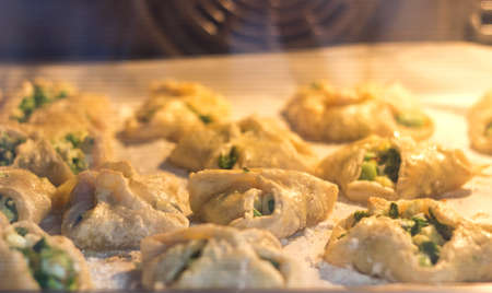 Baking homemade puff pastry cakes with onion and egg in hot oven. Blurred backgroundの写真素材