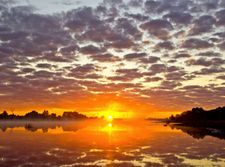 Beautiful summer landscape with tranquility sunrise over the river with hazeの写真素材