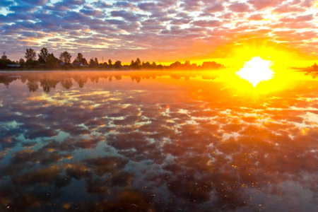 Beautiful summer landscape with tranquility sunrise over the river with haze