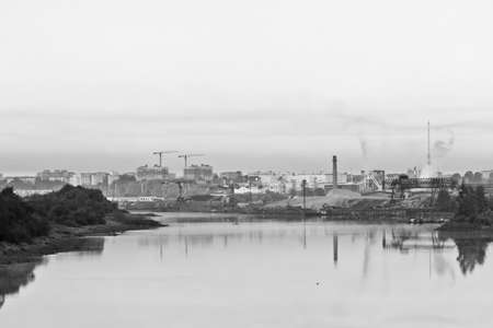 Cityscape with river and factory. Image toned in black and white colorsの写真素材