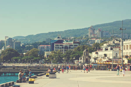 tourists walking on seaside embankment in Yalta city. Yalta is resort city on the coast of Black Sea on the Crimean peninsula. Image toned in retro styleのeditorial素材
