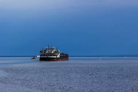 Summer stormy landscape with commercial ship on riverの写真素材