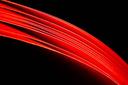 red A4 paper illuminated with LED lights seen as red curved in black backgroundの写真素材