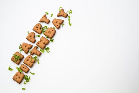 the words Happy Birthday made by brown biscuits and green leaves slanting on left side of white surface in landscape orientationの写真素材