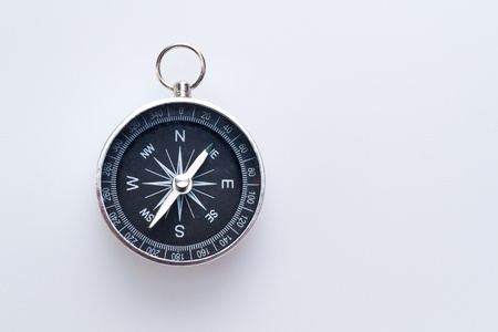 a simple metal compass hanged on white surface with copy spaceの写真素材