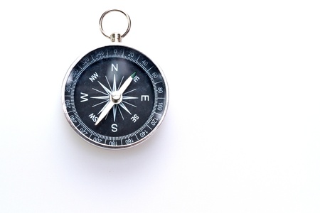 a simple metal compass hanged on white surface with copy spaceの写真素材