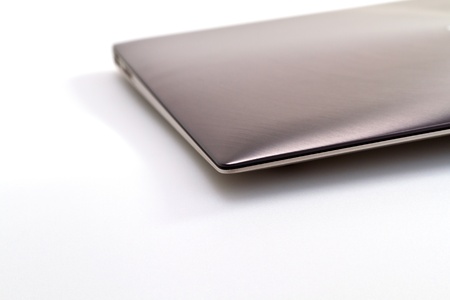 a modern metal laptop with closed lid on white background for abstract backgroundの写真素材
