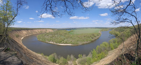 River bend in deep forest under blue sky with trees on the banks
