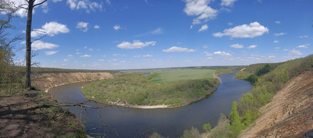 River bend in deep forest under blue sky with trees on the banks