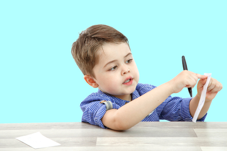 a little boy of preschool age shows a leaf on which he wrote or painted somethingの写真素材