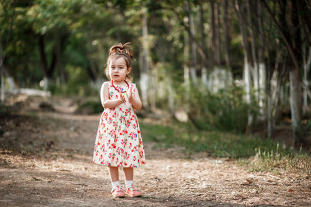 portrait of a little cute Caucasian girl in vintage clothes posing in the woodsの写真素材