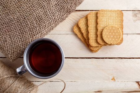 tea in vintage mug and cookies on canvasの写真素材