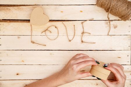 women's hands spread hearts and the word love of threads on a light wooden background. the view from the topの写真素材