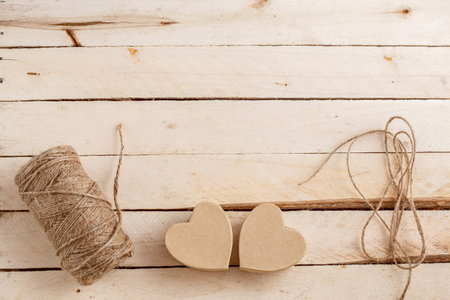 brown biodegradable heart shaped gift boxes with threads for packaging on light wooden background