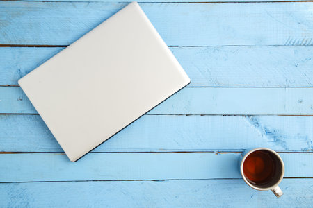 gray laptop and a Cup of drink on a blue wooden background. the view from the top