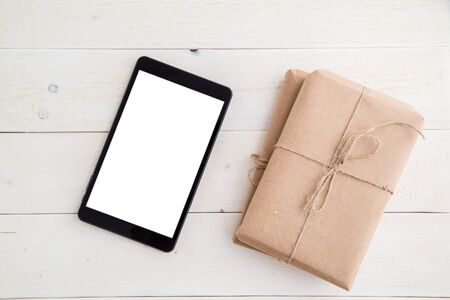 parcel,gift Packed in eco-friendly paper and tablet on light wooden background. the view from the topの写真素材