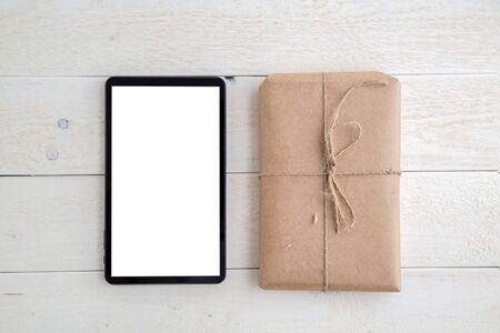 parcel,gift Packed in eco-friendly paper and tablet on light wooden background. the view from the topの写真素材