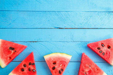 red scarlet watermelon pieces on blue wooden vintage background. summer concept. the view from the...