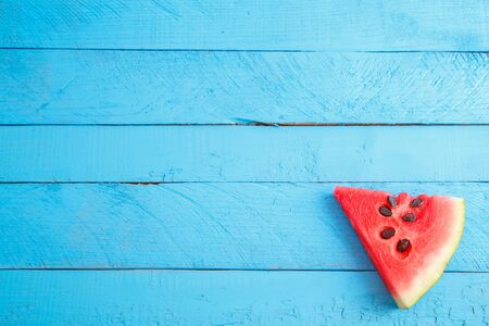 red scarlet watermelon pieces on blue wooden vintage background. summer concept. the view from the topの写真素材