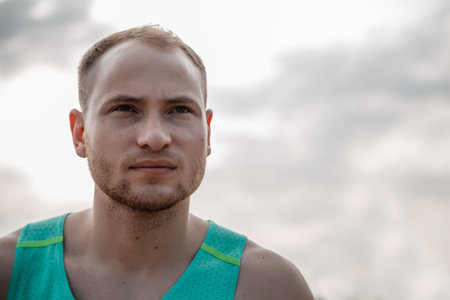 portrait of Caucasian guy in an azure t-shirt and black shorts running over rough terrain. training...