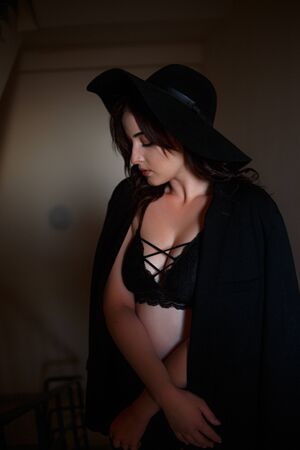 Young beautiful woman in black jacket with black hat and black underwear posing in the sunsetの写真素材