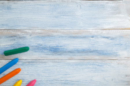 school children's concept. colored pencils and crayons on a blue and white scuffed vintage wooden...