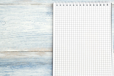 paper notebook with space for text on a light blue old wooden background. top view. flat lay