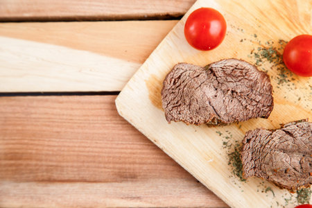 chunks of deep-fried meat, steak on a wooden tray with spices and cherry tomatoes