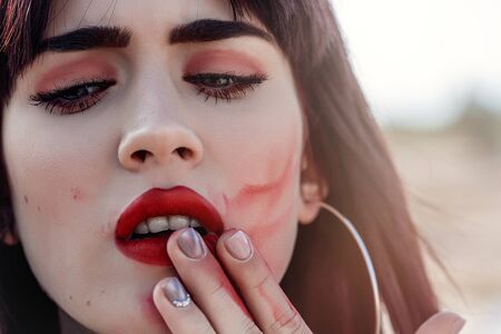 street portrait of beautiful young Caucasian brown haired girl with smeared lipstick on her faceの写真素材
