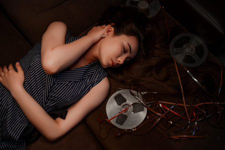 portrait of a young Asian girl in a blue striped dress lying on the couch next to the reels with...