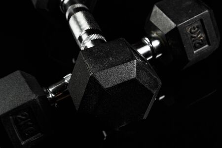 sports dumbbells with black rubber handle on black isolated backgroundの写真素材